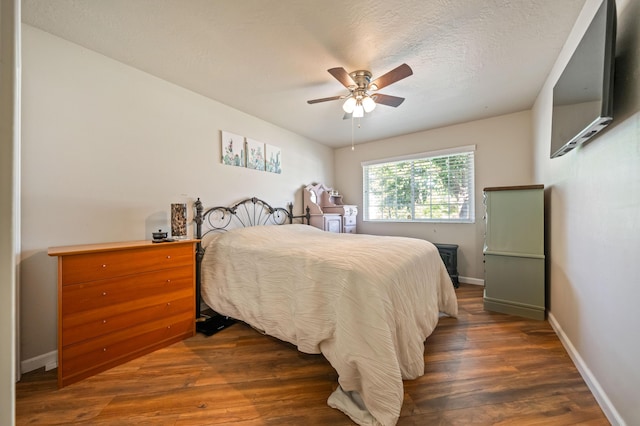 bedroom with a ceiling fan, baseboards, and dark wood-type flooring