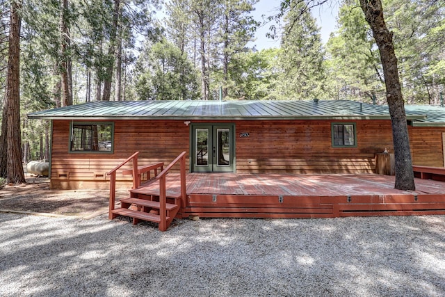 rear view of property with a wooden deck, metal roof, and a standing seam roof
