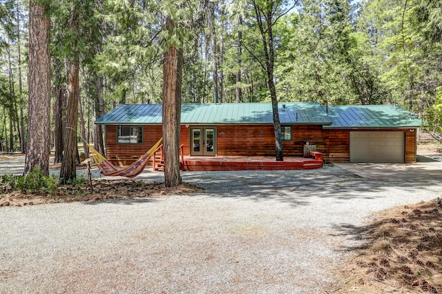 view of front facade with an attached garage, driveway, french doors, and metal roof