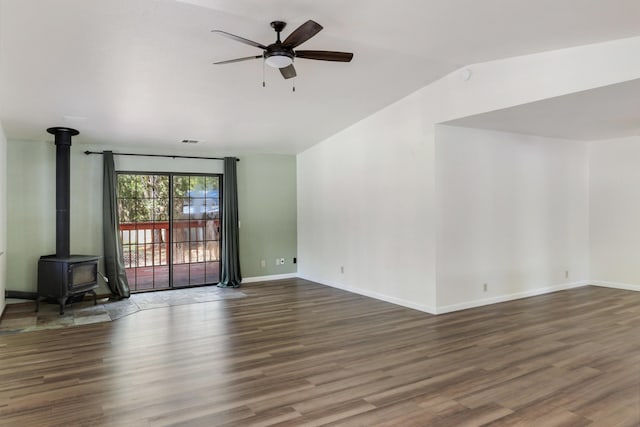 unfurnished living room featuring ceiling fan, wood finished floors, a wood stove, lofted ceiling, and baseboards