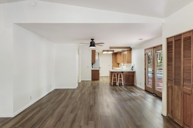 living area featuring dark wood finished floors, baseboards, and a ceiling fan