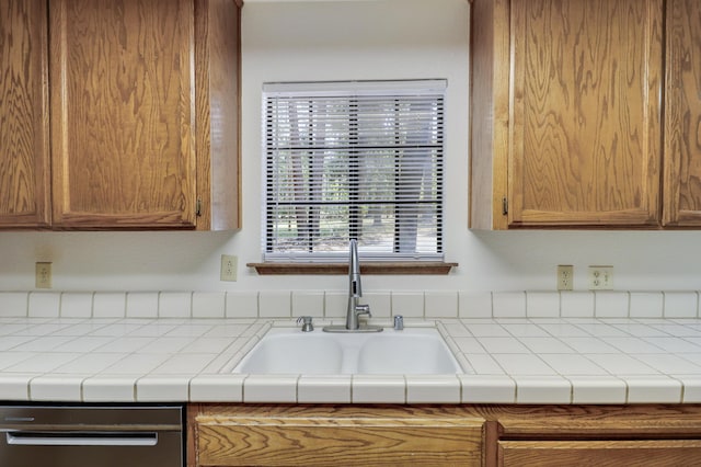kitchen with a sink, dishwashing machine, and brown cabinets