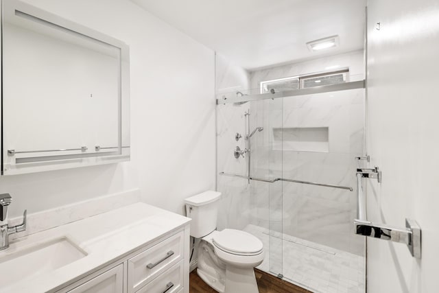 full bath featuring toilet, vanity, a marble finish shower, and wood finished floors