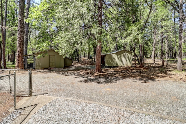 view of yard featuring a shed, fence, an outbuilding, and a gate