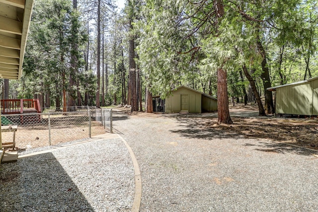 view of yard featuring a storage shed, an outdoor structure, fence, and a wooden deck