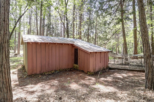 view of outdoor structure with fence, an outdoor structure, and a wooded view