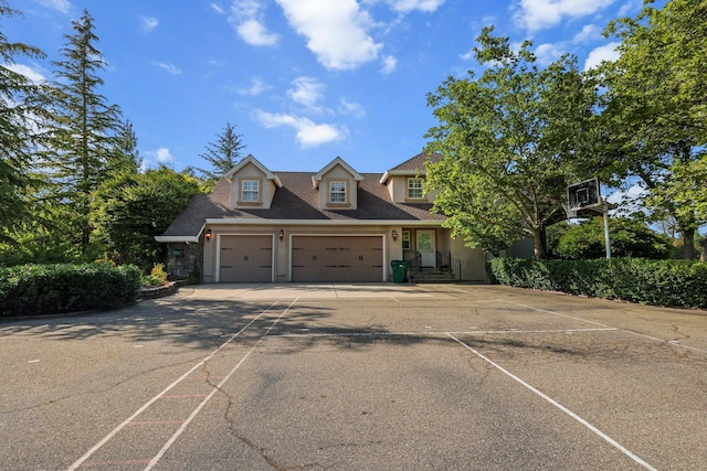 new england style home featuring an attached garage and driveway