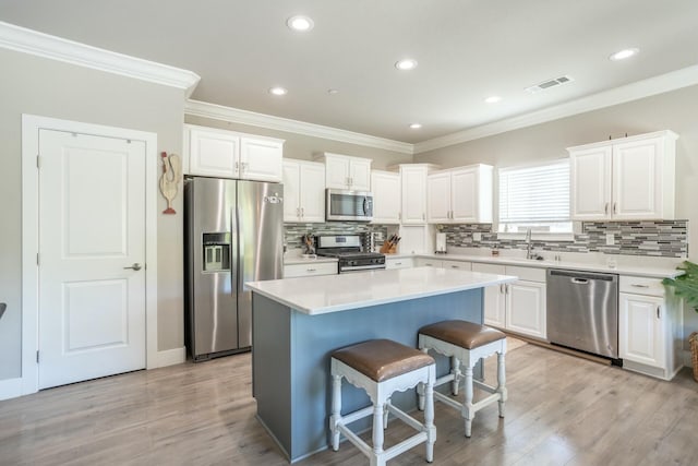 20295 Ballentine Dr, Anderson, CA 96007 - kitchen featuring visible vents, crown molding, a kitchen bar, white cabinetry, and stainless steel appliances