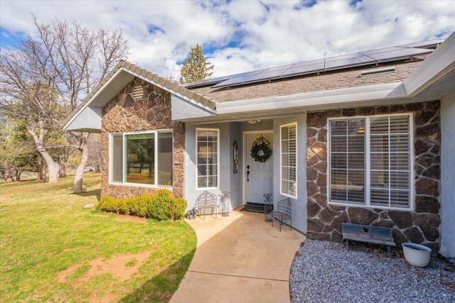 view of exterior entry featuring roof mounted solar panels, a lawn, and stone siding