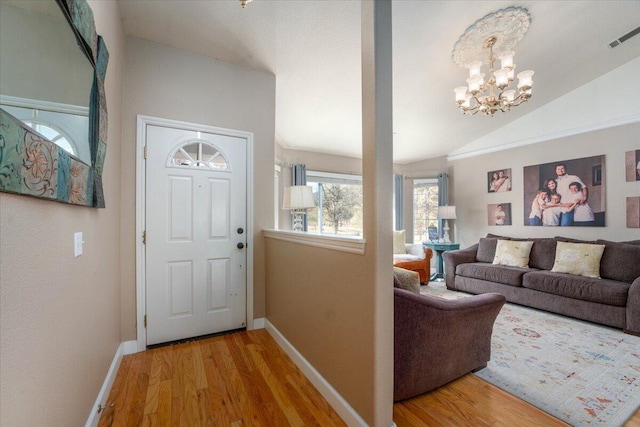 entryway with light wood-style flooring, vaulted ceiling, baseboards, visible vents, and a notable chandelier