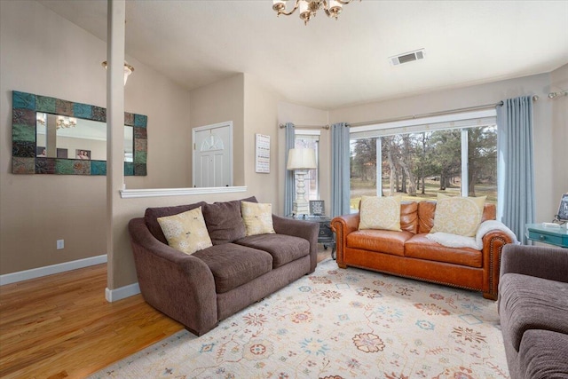 living area featuring baseboards, visible vents, a notable chandelier, and light wood-style flooring