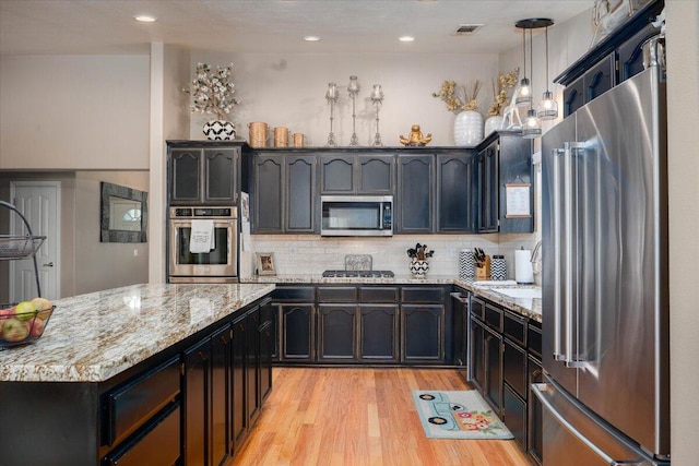 kitchen featuring light stone countertops, stainless steel appliances, light wood-type flooring, visible vents, and backsplash