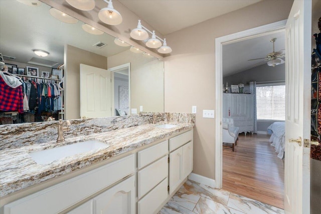 bathroom with double vanity, a spacious closet, a ceiling fan, and a sink
