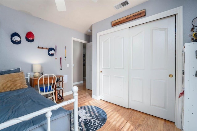 bedroom featuring visible vents, ceiling fan, baseboards, a closet, and light wood finished floors