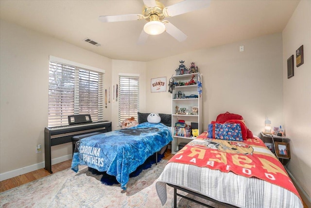 bedroom featuring wood finished floors, visible vents, a ceiling fan, and baseboards