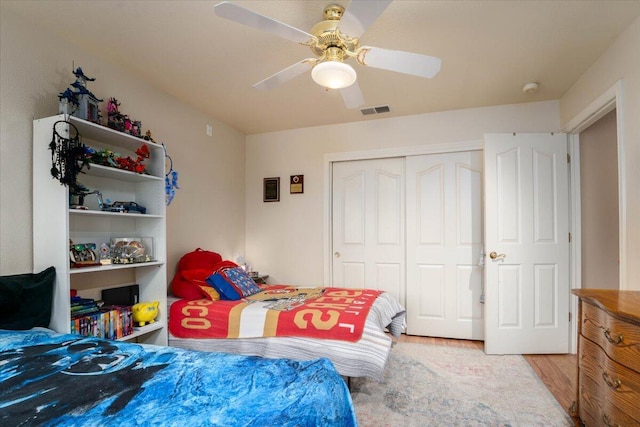 bedroom with light wood finished floors, a closet, visible vents, and a ceiling fan