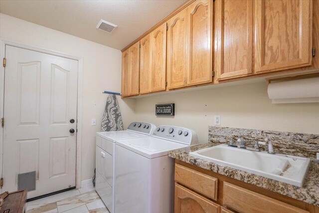 laundry area featuring visible vents, separate washer and dryer, cabinet space, and a sink