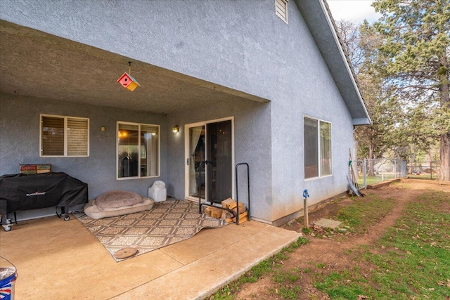 back of property with stucco siding, fence, and a patio