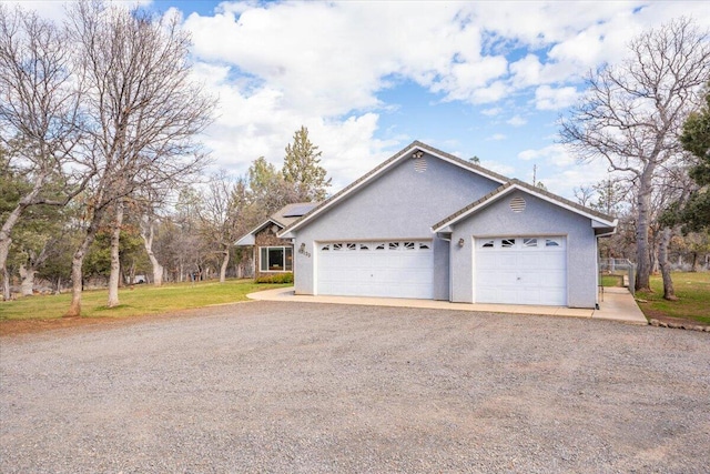 view of front facade with stucco siding, a front lawn, driveway, and solar panels