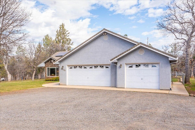 ranch-style home with solar panels, a garage, and stucco siding