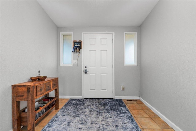 foyer entrance with light tile patterned flooring and baseboards
