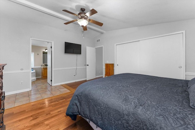 bedroom featuring visible vents, a closet, wood finished floors, ceiling fan, and vaulted ceiling