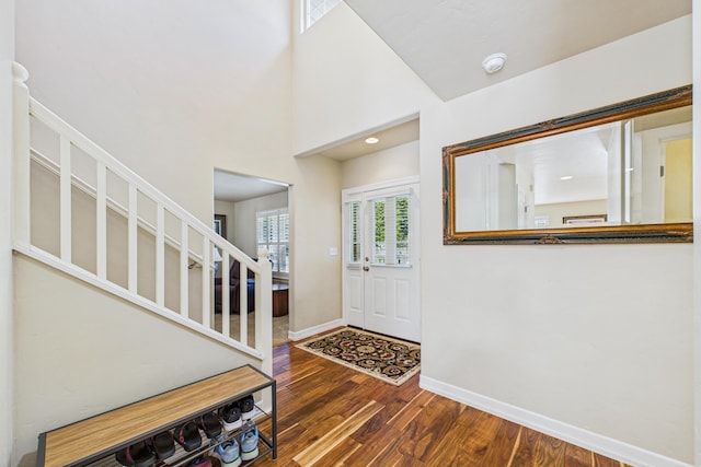 foyer entrance featuring baseboards, wood finished floors, and stairs