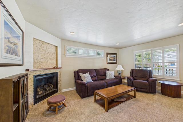 living area with a glass covered fireplace, baseboards, carpet floors, and a healthy amount of sunlight