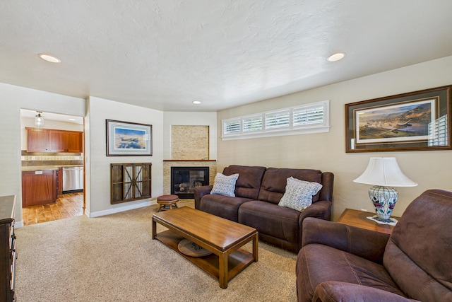 living area featuring recessed lighting, a glass covered fireplace, light colored carpet, and baseboards