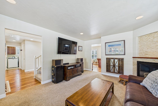 living area featuring recessed lighting, stairway, a glass covered fireplace, light carpet, and baseboards