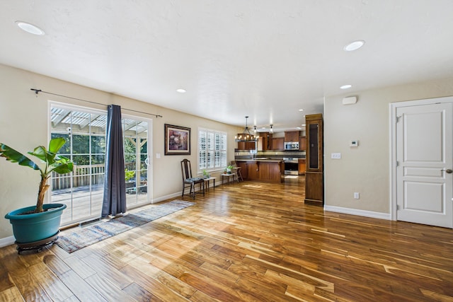 unfurnished living room featuring hardwood / wood-style floors, recessed lighting, and baseboards