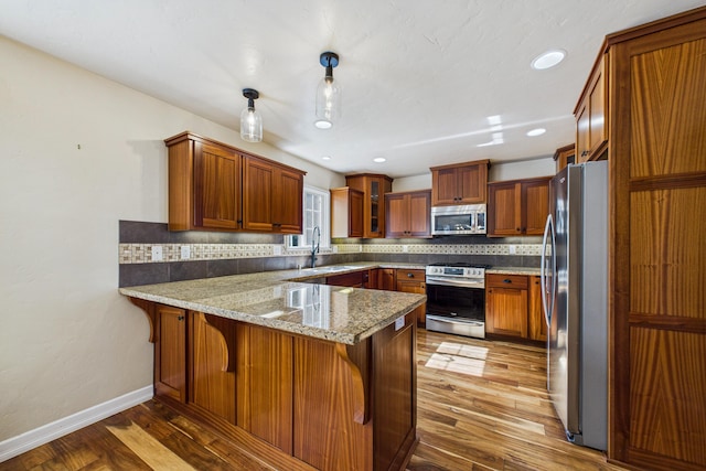 kitchen featuring a peninsula, appliances with stainless steel finishes, decorative backsplash, and light wood-style floors