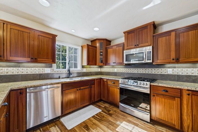kitchen featuring dark wood-style floors, a sink, light stone counters, and appliances with stainless steel finishes