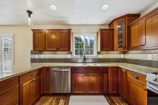 kitchen featuring light stone countertops, a sink, appliances with stainless steel finishes, and dark wood-style flooring