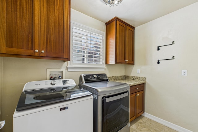 laundry area with light tile patterned flooring, cabinet space, washing machine and clothes dryer, and baseboards