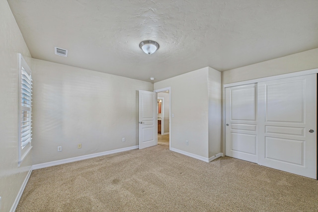 unfurnished bedroom with visible vents, carpet, and baseboards