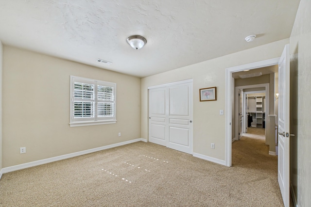 unfurnished bedroom featuring baseboards, visible vents, carpet floors, and a closet