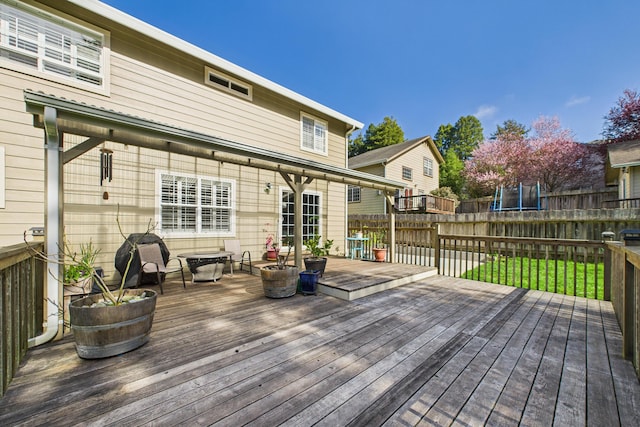 wooden terrace featuring a trampoline and fence