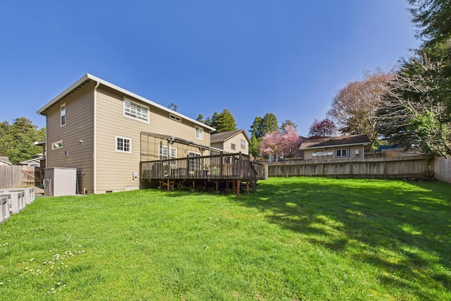 rear view of property featuring a deck, a fenced backyard, and a lawn