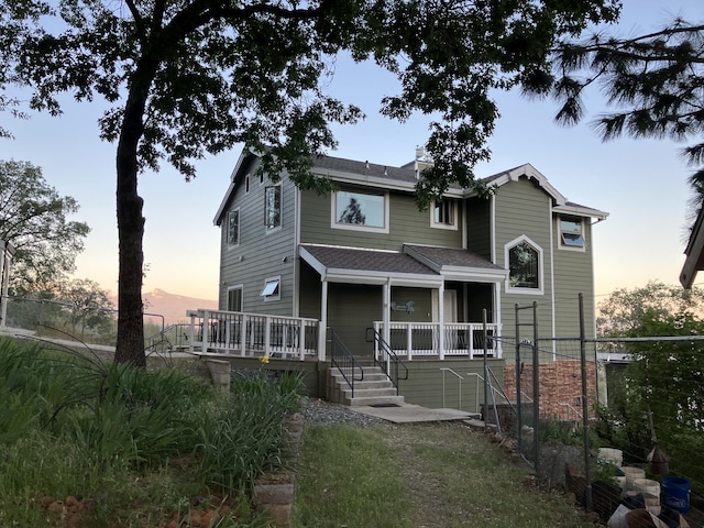 view of front facade featuring a shingled roof and fence