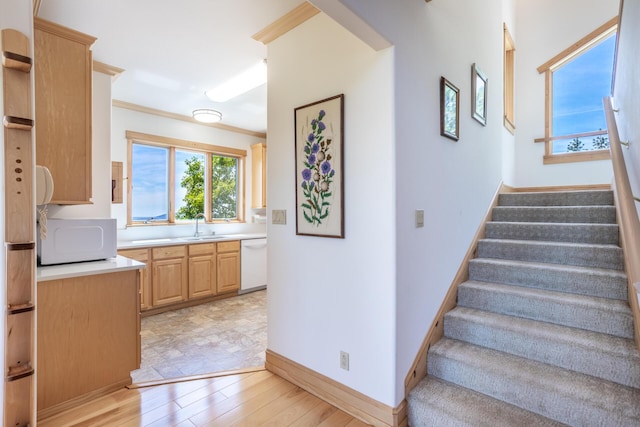 stairs with baseboards, wood finished floors, and crown molding