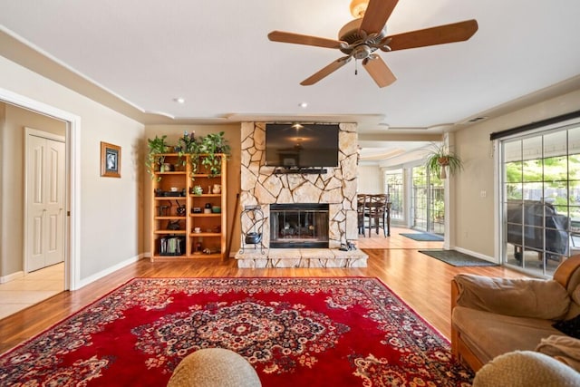 3301 Bridger Dr, Redding, CA 96002 - living area featuring wood finished floors, a stone fireplace, baseboards, and a ceiling fan