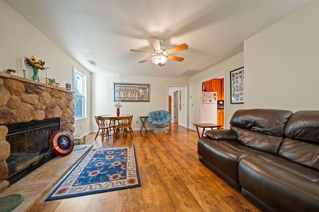 3301 Bridger Dr, Redding, CA 96002 - living area featuring a ceiling fan, light wood-style floors, a stone fireplace, and baseboards