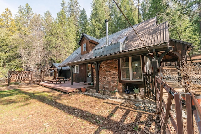 rear view of property with metal roof, a deck, and brick siding