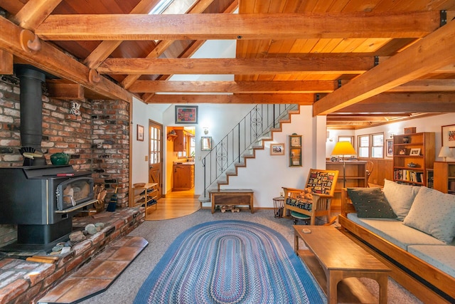 carpeted living area featuring a wood stove, wood ceiling, stairs, and beamed ceiling