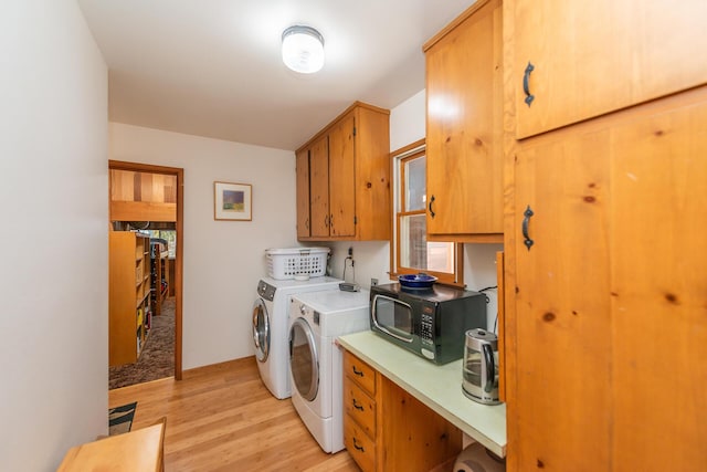 washroom with light wood-type flooring, cabinet space, and washer and clothes dryer