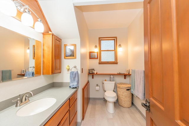 bathroom with baseboards, wood finished floors, toilet, and vanity