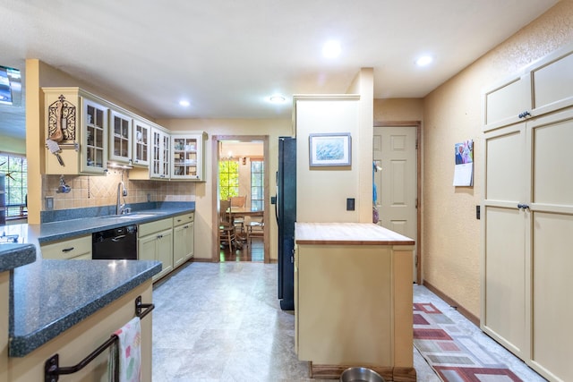 kitchen featuring tasteful backsplash, a sink, black appliances, glass insert cabinets, and recessed lighting