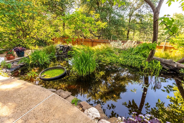 view of community with a small pond and fence