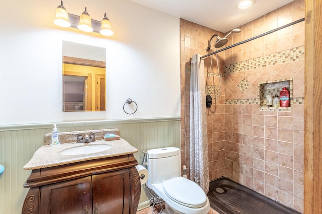 bathroom with vanity, toilet, wainscoting, and a stall shower
